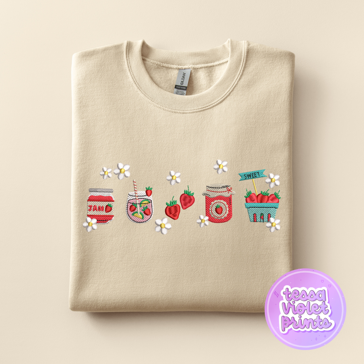 A beige sweatshirt with a row of colorful jars and strawberries embroidered on it, along with white flowers.