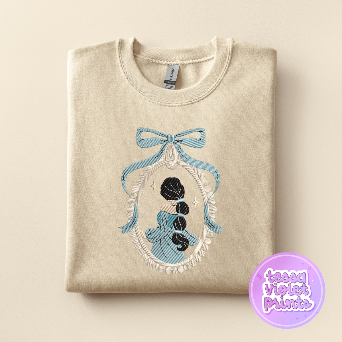 A beige sweater with a blue bow and a framed image of a woman with long hair, which appears to be a design or pattern.