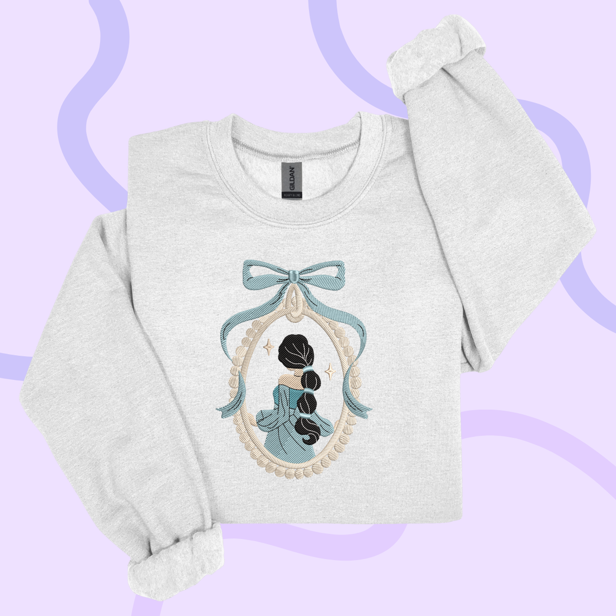 A white sweatshirt with a blue bow and a framed illustration of a woman on the front.