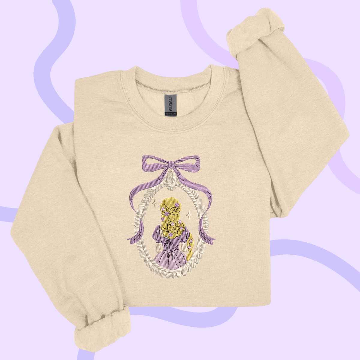 A beige sweater with a purple bow and a framed illustration of a blonde woman wearing a purple dress.