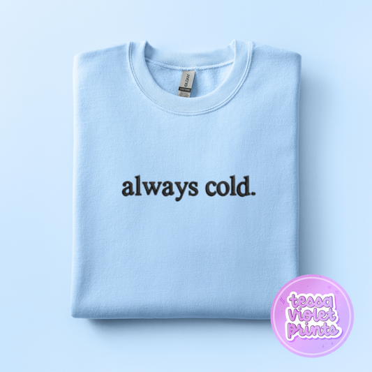 A light blue sweatshirt with the text "always cold" printed on it.