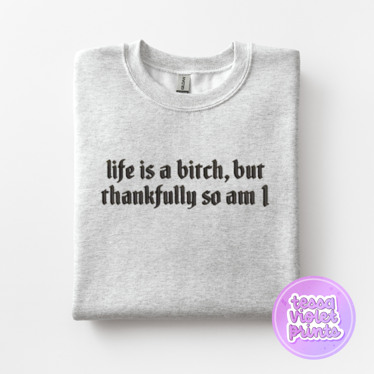 A gray sweatshirt with the text "life is a bitch, but thankfully so am I" printed on it.