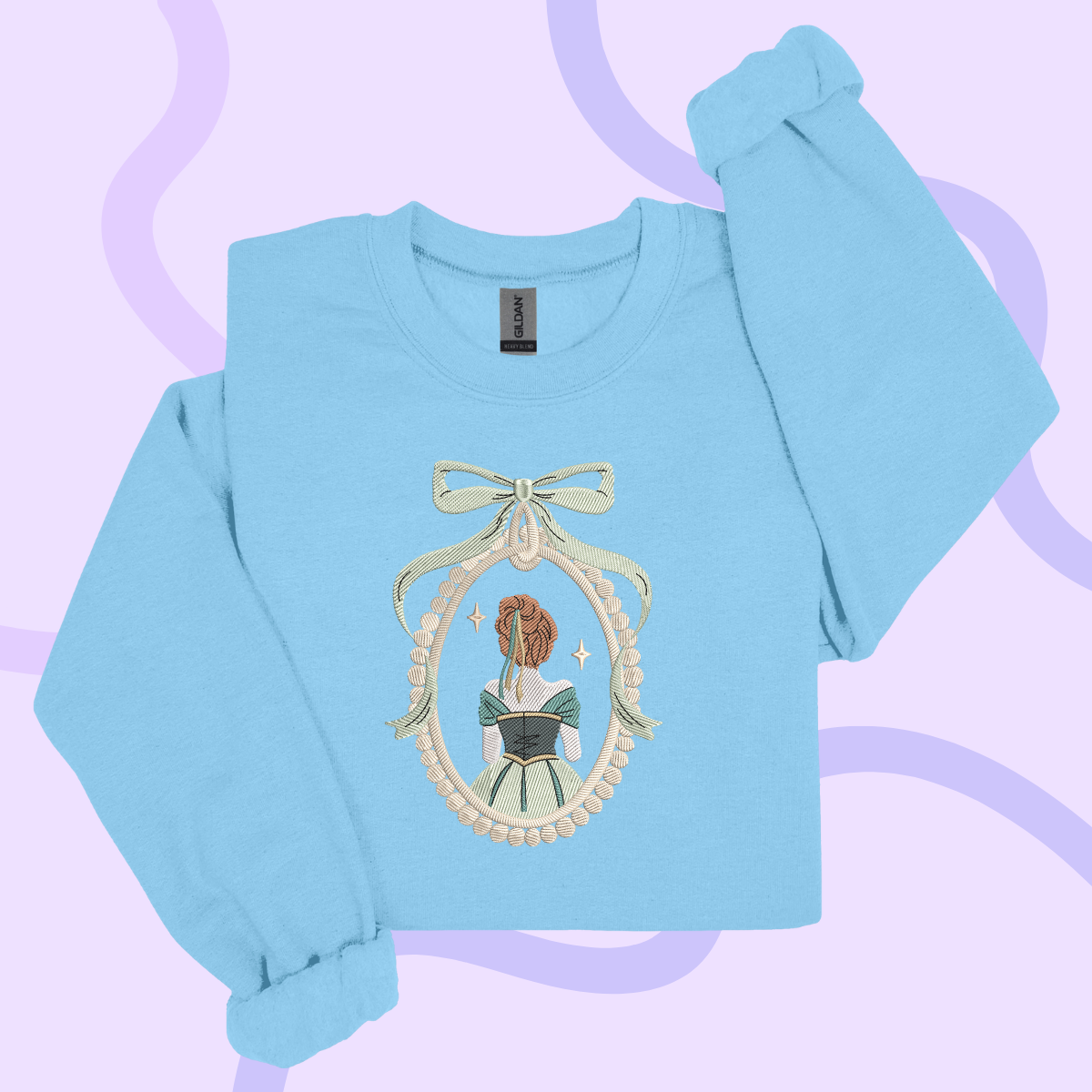 A light blue long-sleeved shirt with a decorative embroidered design featuring a woman's face and a bow.