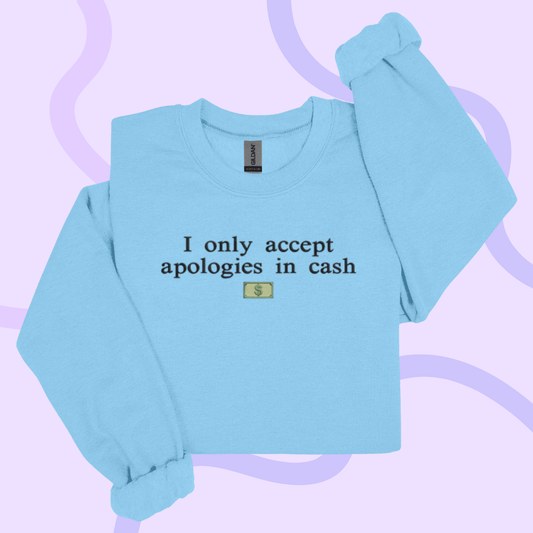 A light blue long-sleeved shirt with the text "I only accept apologies in cash" printed on it.