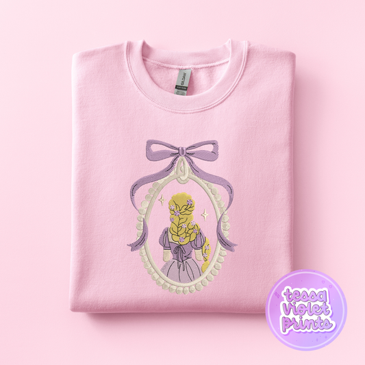 A pink sweatshirt with a purple bow and a framed image of a blonde woman with a flower in her hair.