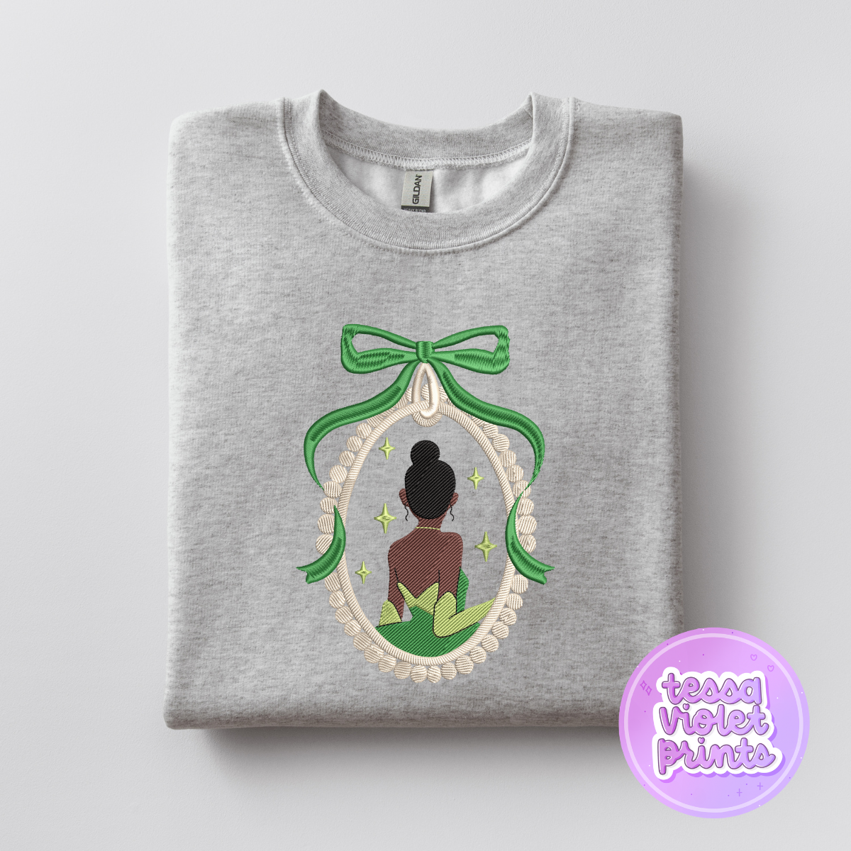 A gray sweatshirt with a green bow and a framed image of a woman with a green ribbon around her neck.