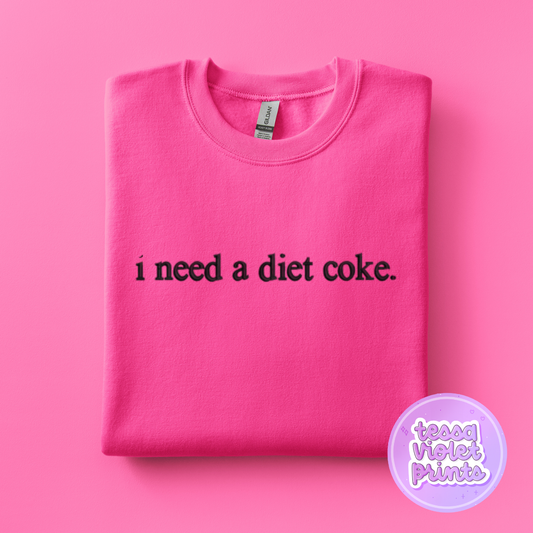 A pink sweatshirt with the text "I need a diet coke" printed on it.