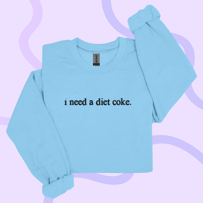 A light blue long-sleeved shirt with the text "I need a diet coke" printed on it.