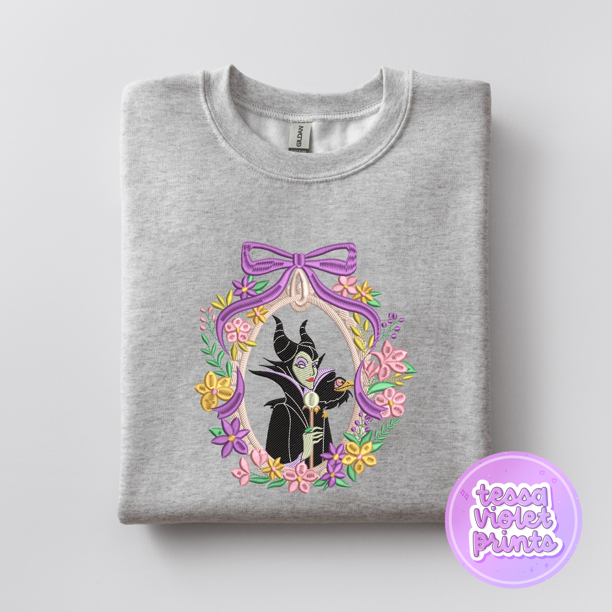A gray sweatshirt with a graphic design featuring a character from the Disney film "Maleficent" surrounded by a floral border.