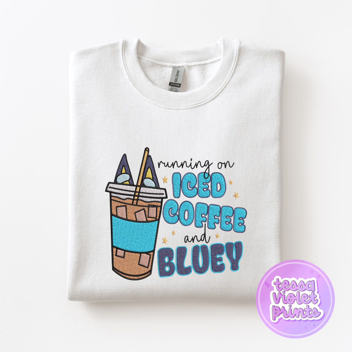 A white sweatshirt with a graphic design depicting a cup of iced coffee and the text "running on iced coffee and bluey".