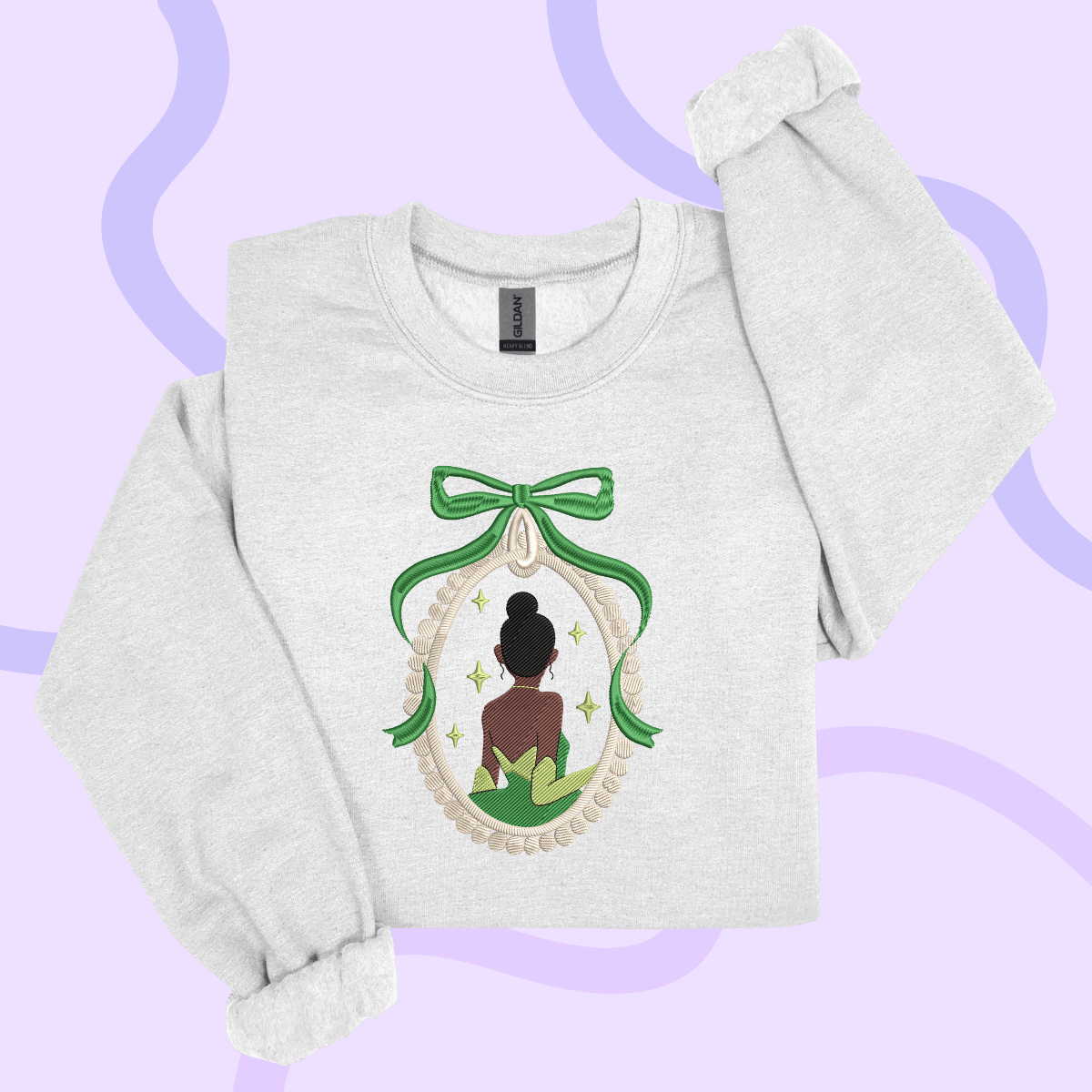 A white sweatshirt with a graphic design featuring a woman in a green dress and a bow, surrounded by stars and a green ribbon.