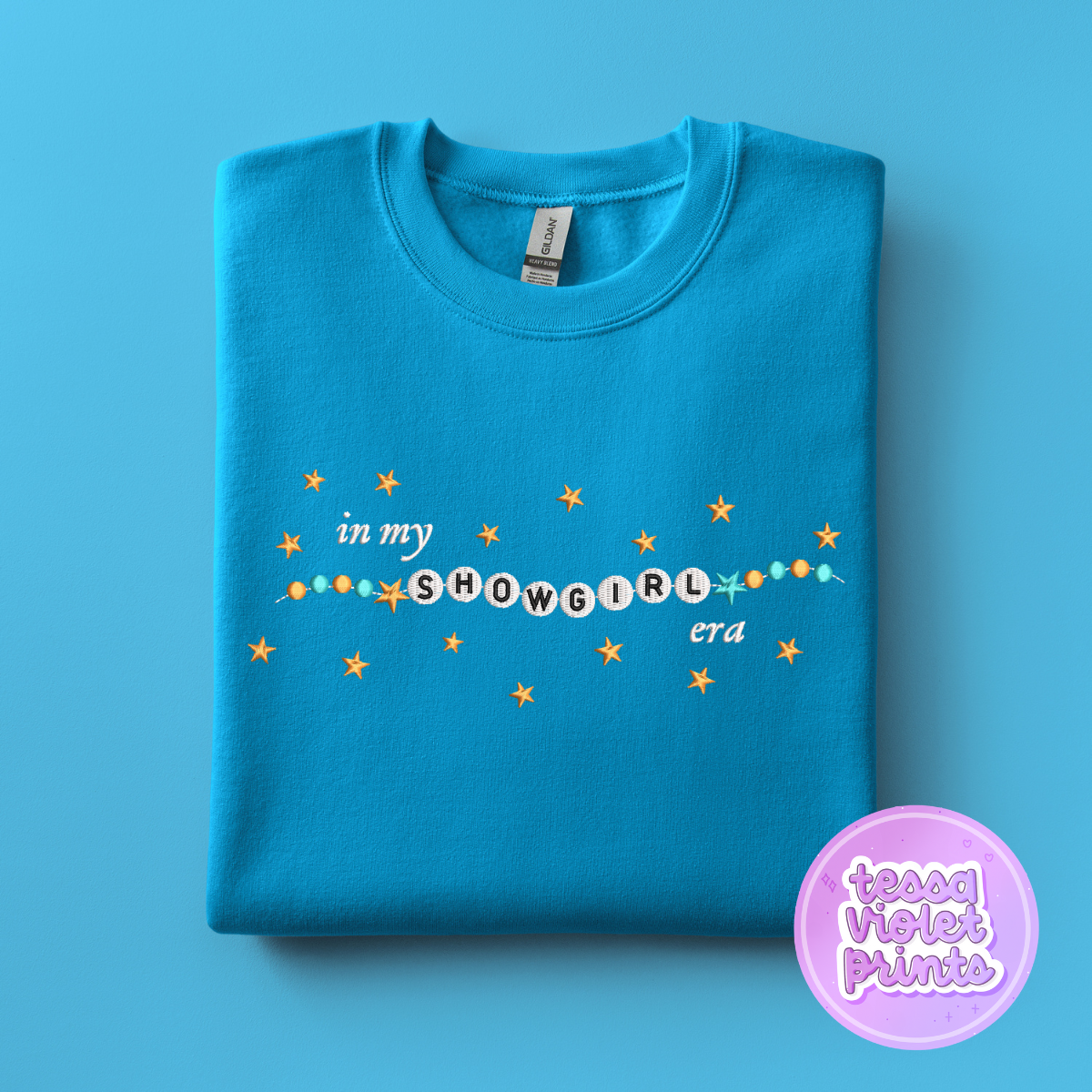 A blue t-shirt with the text "in my SHOWGIRL era" printed on it, along with small stars.