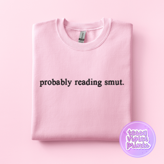 A pink sweatshirt with the text "probably reading smut" printed on it.