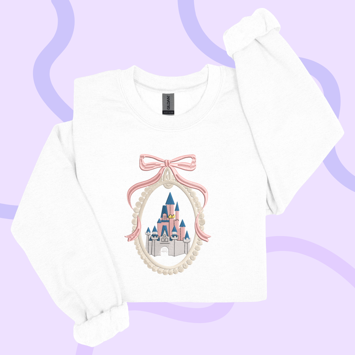 A white long-sleeved shirt with a pink bow and a castle embroidered on it, set against a purple background.