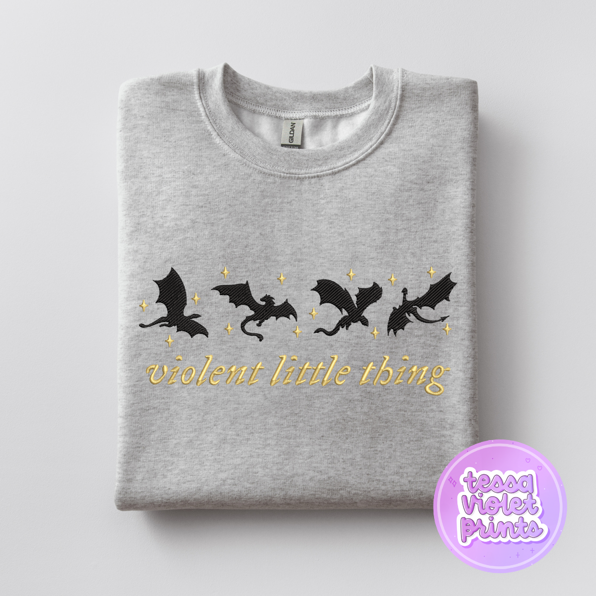 A gray sweatshirt with a graphic design featuring silhouettes of four black bats and stars, along with the text "violent little thing" printed on it.