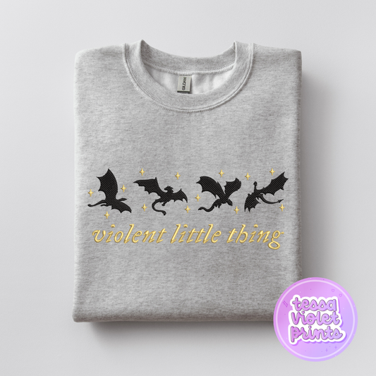 A gray sweatshirt with a graphic design featuring silhouettes of four black bats and stars, along with the text "violent little thing" printed on it.