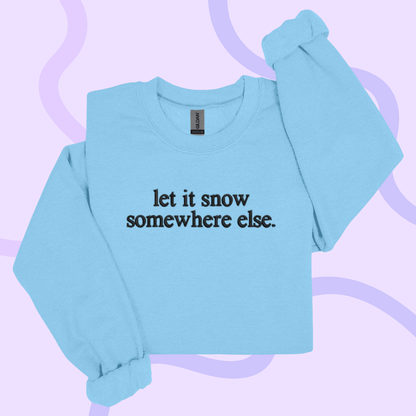 A light blue long-sleeved shirt with the text "let it snow somewhere else" printed on it.